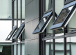 Row of automatic opening vents with chain actuators, open on the glazed facade of a building