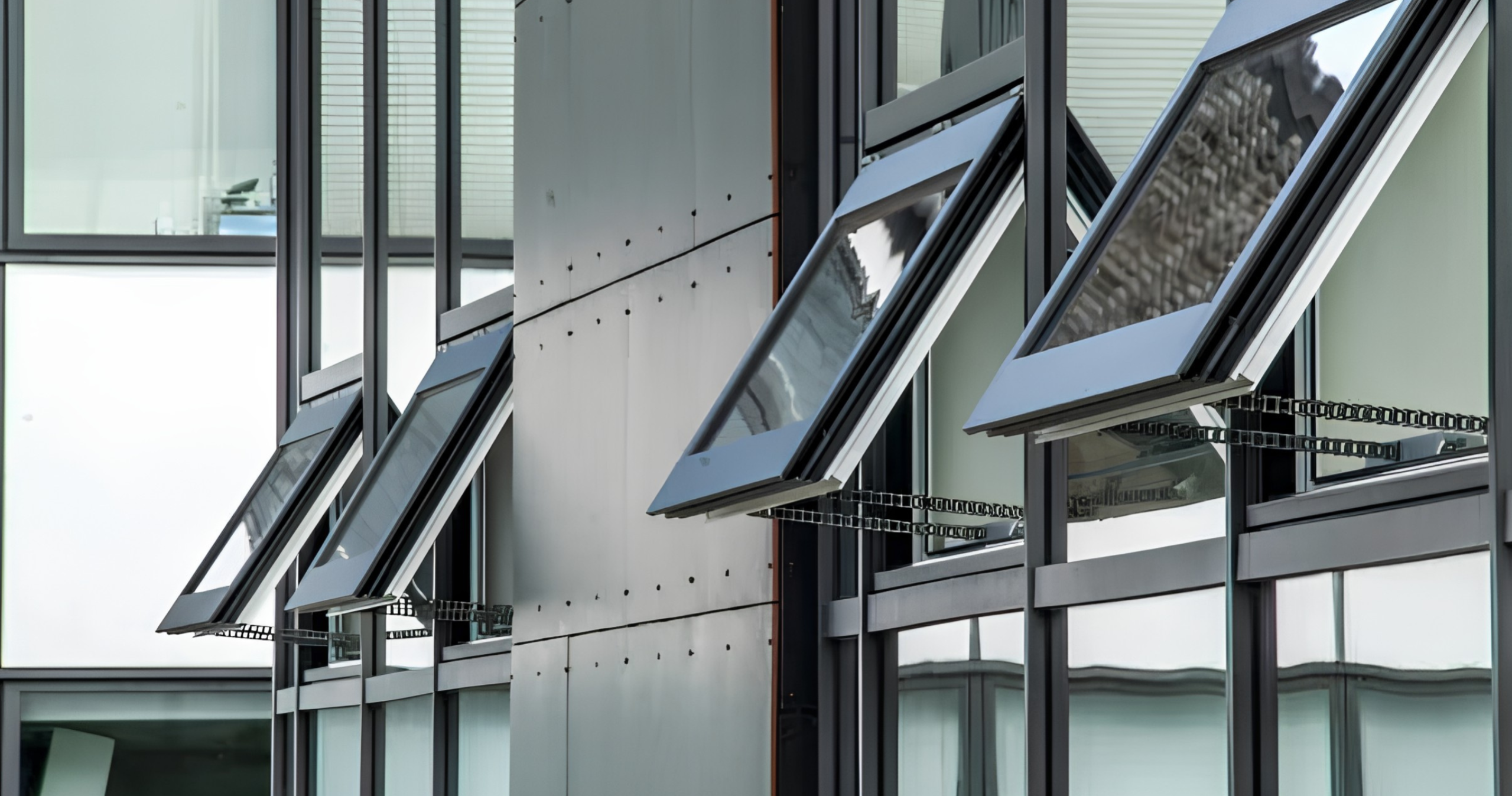 DALA Blog AOVs in an Old Building Row of automatic opening vents with chain actuators, open on the glazed facade of a building