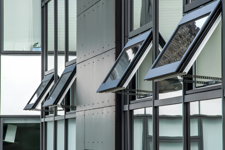 Row of automatic opening vents with chain actuators, open on the glazed facade of a building