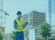 Clerk of Works reviewing inspection notes on a clipboard in front of a high-rise building under construction, illustrating independent site inspection during new-build residential construction.