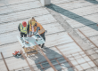 Three construction professionals in hi-vis jackets reviewing building plans on an open construction site, viewed from above.