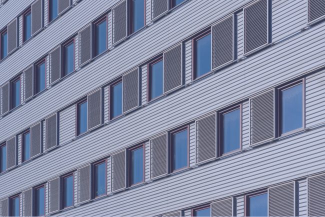 Cladding panels and windows on a multi-storey residential building Close-up of cladding panels and windows across multiple floors of a residential building.